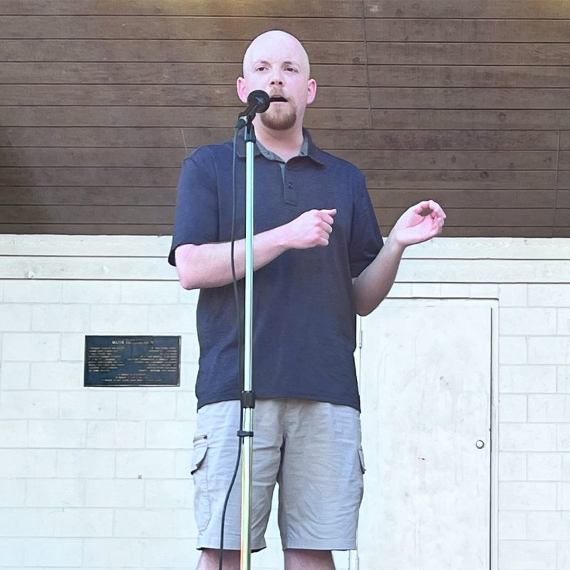 Stephan Tucker shares a story at a microphone
