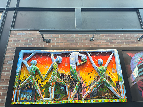 The photo is of a mural on a brick wall. It features vibrant colors and intricate designs.